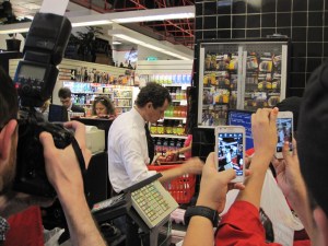 Photographers snap as Weiner pays for his items.