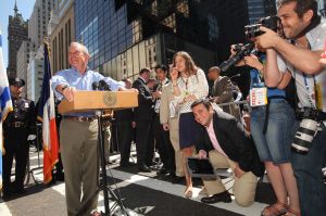 Mayor Michael Bloomberg at a press conference as Sally Goldenberg looks on. (Photo: Facebook)