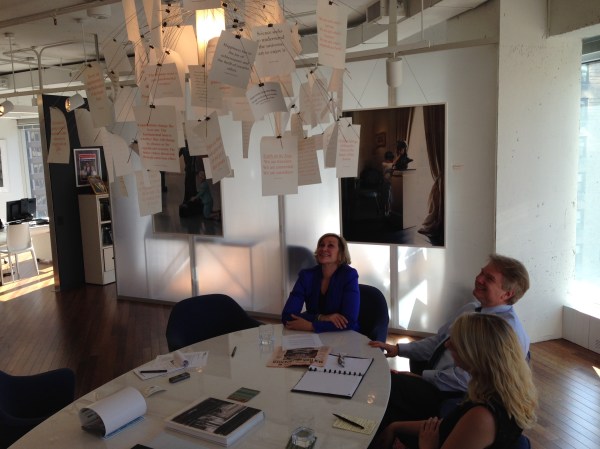 Ms. Tisch, her favorite pink newspaper on the table beneath a light filled with inspired maxims, at the Illumination Fund offices.