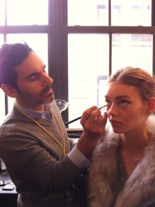 James Kaliardos puts makeup on a model before a show.
