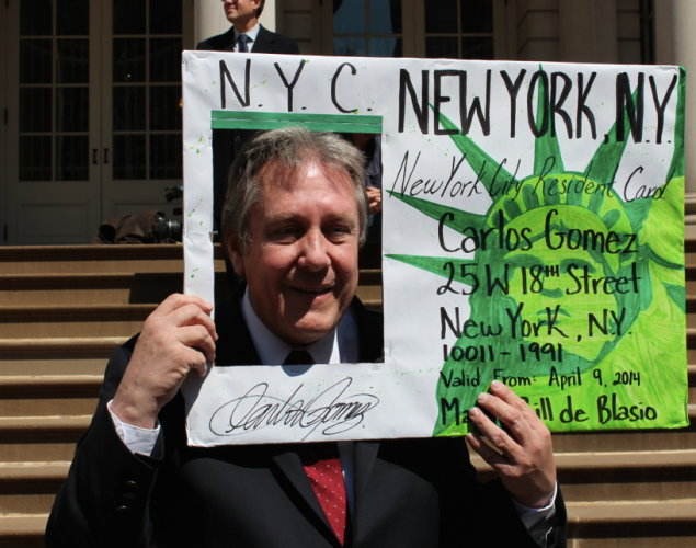 Councilman Danny Dromm holds up a giant municipal ID card prop. (Photo: Kelly Well)
