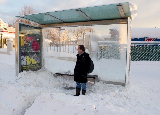 A man waits at a bus stop in the Bronx. (Photo via Getty Images)