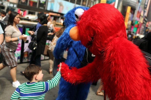 An Elmo costume character greets a child in Times Square. (Photo:Spencer Platt/Getty Images)