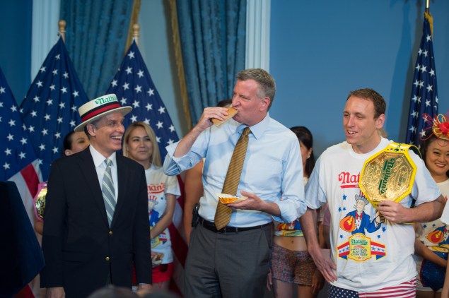 Mayor Bill de Blasio eats a hot dog between contest co-founder George Shea and Joey Chestnut. (Rob Bennett/Office of the Mayor)