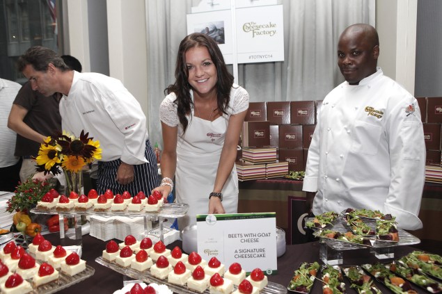 Chef Kerry Heffernan (left) prepares more samples as tennis pro Agnieszka Radwanska hands out Cheesecake Factory desserts and chef Jay Hinson looks on. (Photo via Getty)