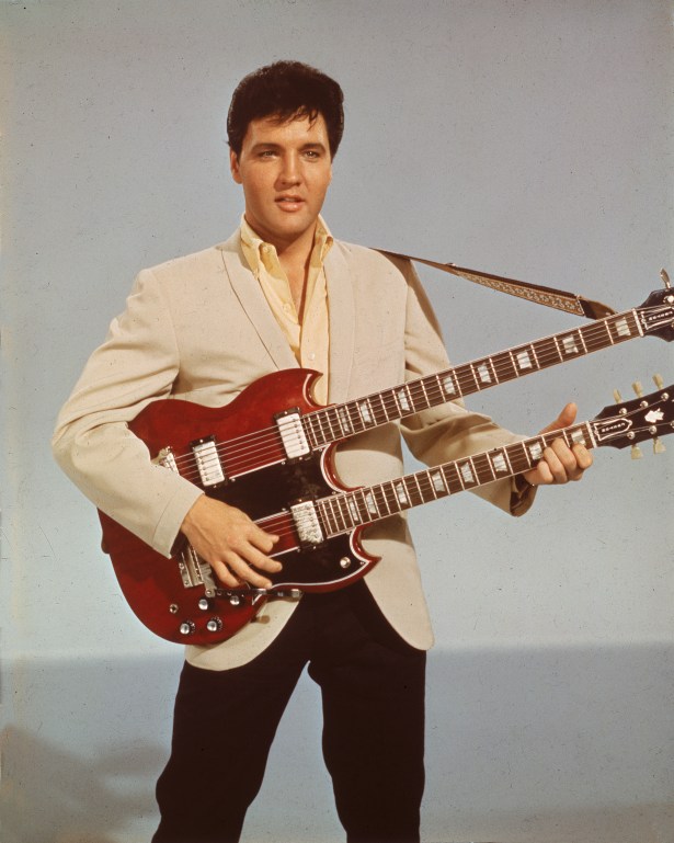 Elvis Presley poses for an iPad picture while holding his iPhone. (Photo via Getty)