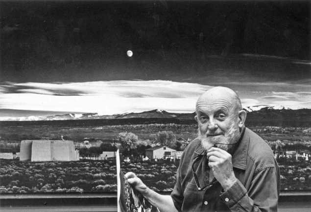 1974:  Portrait of American photographer Ansel Adams (1902 - 1984) standing in front of his landscape photograph, 'Moonrise, Hernandez,' at his home in Carmel, California. He holds a photographic print in one hand, and his eyeglasses in the other.  (Photo by Joe Munroe/Hulton Archive/Getty Images)