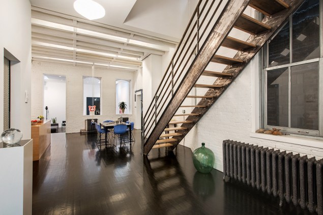 The condo features a 'sculptural' staircase, skylights and painted white brick. 