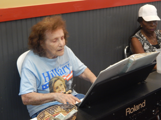 An elderly Clinton supporter plays a halting tune on an electric keyboard inside the market
