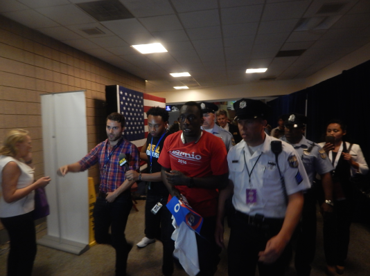 Police escort a Sanders supporter from the convention hall during Clinton's acceptance speech