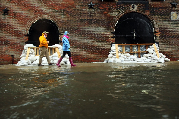NEW YORK, NY - OCTOBER 29: People walk past sandbags on a flooded street as Hurricane Sandy moves closer to the area on October 29, 2012 in the Red Hook section of the Brooklyn borough of New York City. The storm, which threatens 50 million people in the eastern third of the U.S., is expected to bring days of rain, high winds and possibly heavy snow. New York Governor Andrew Cuomo announced the closure of all New York City bus, subway and commuter rail service as of Sunday evening. (Photo by Spencer Platt/Getty Images)