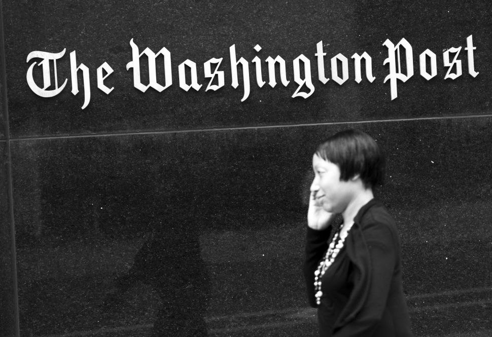 A woman walks past the Washington Post Building August 6, 2013 in Washington, DC, the day after it was announced that Amazon.com founder and CEO Jeff Bezos had agreed to purchase the newspaper.