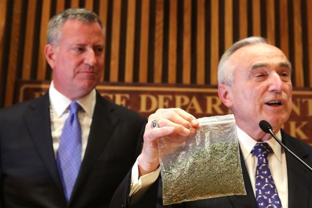 Mayor Bill de Blasio looks on as NYPD Commissioner Bill Bratton holds up a bag of oregano. 