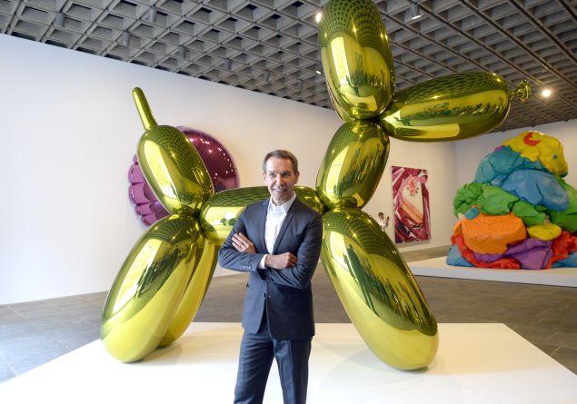 Jeff Koons poses with one of his sculptures at the Whitney Museum of American Art in 2014. (Photo by: Timothy A. Clary/AFP/Getty Images)