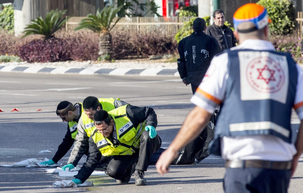 Israeli emergency services personnel clean the sidewalk at the scene of an attack after a Palestinian man stabbed at least five people on a Tel Aviv bus on January 21, 2015. (Getty Images)
