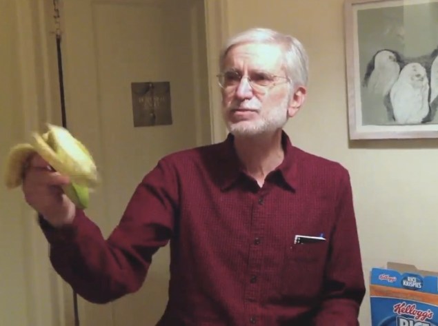 Barry Newman brandishes a baby banana. (Screenshot via Wall Street Journal)