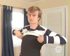 Liam putting on an  ID Clothing shirt. (Screengrab:YouTube)