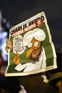PARIS, FRANCE - JANUARY 07: A man holds the cover of a Charlie Hebdo magazine which reads '100 lashes if you are not dying of laughter' during a vigil at the Place de la Republique (Republic Square) for victims of the terrorist attack, on January 7, 2015 in Paris, France. Twelve people were killed, including two police officers, after gunmen opened fire at the offices of the French satirical publication Charlie Hebdo. (Photo by Dan Kitwood/Getty Images)