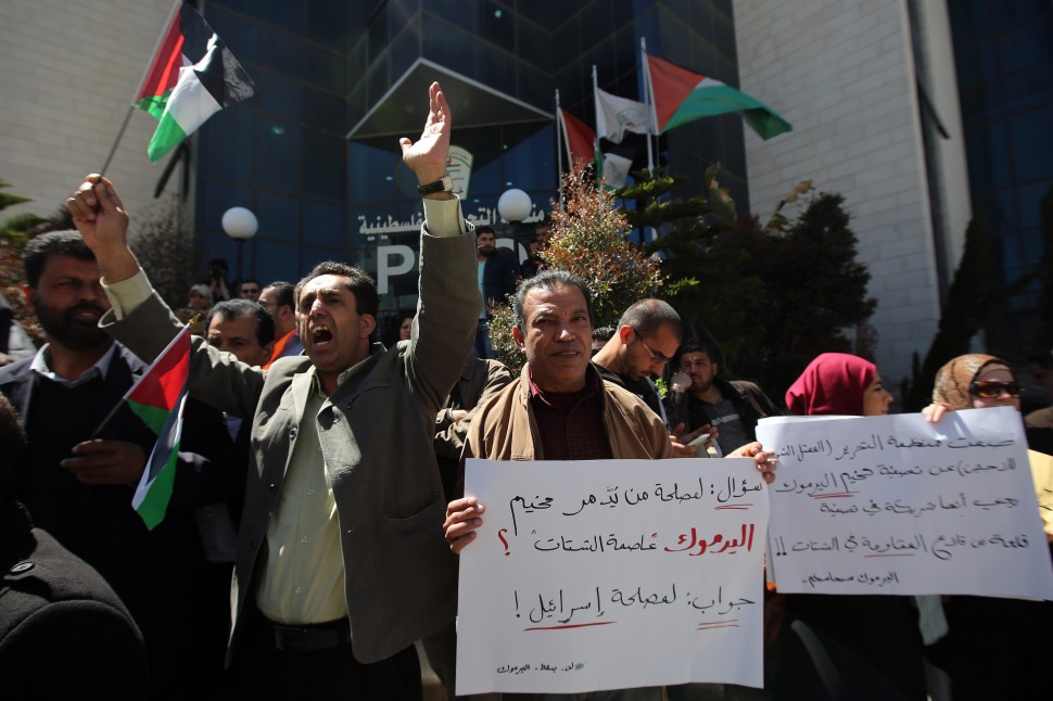 Palestinians shout slogans as they hold banners during a gathering in solidarity with the Palestinians living in Syria's Yarmouk camp, which is besieged by government forces and has been largely overrun by jihadist fighters, on April 5, 2015 outside Palestinian Liberation Organization (PLO) headquarters the in the city of Ramallah in the West Bank. AFP PHOTO / ABBAS MOMANI        (Photo credit should read ABBAS MOMANI/AFP/Getty Images)