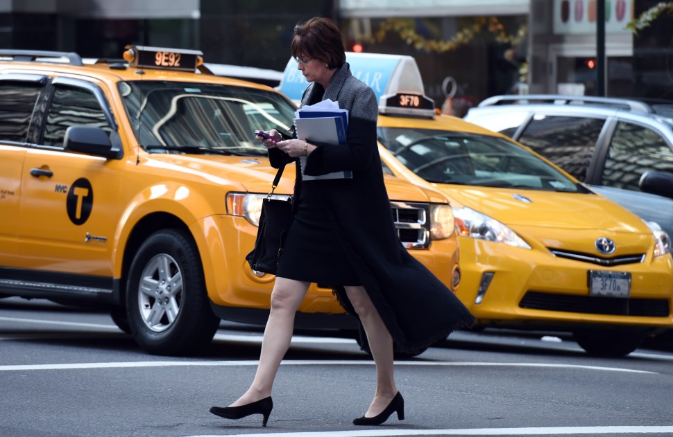 Hail a cab or ping your smart phone? A woman uses her smartphone while crossing a street corner on November 13, 2014 in New York. (DON EMMERT/AFP/Getty Images)
