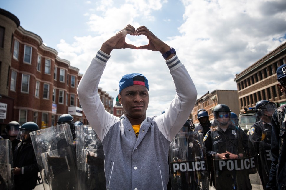 A man makes a heart shape with his hands during a protest near the CVS pharmacy that was set on fire yesterday during rioting after the funeral of Freddie Gray, on April 28, 2015 in Baltimore, Maryland.  (Photo: Andrew Burton/Getty Images)