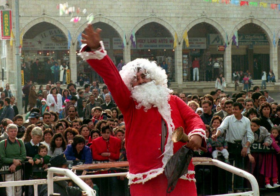 BETHLEHEM: A Palestinian Santa Claus throws confetti, December 24, 1993, to one of the largest crowds ever to watch the Latin Christmas procession since the start of the Intifada in 1987. (SVEN NACKSTRAND/AFP/Getty Images)