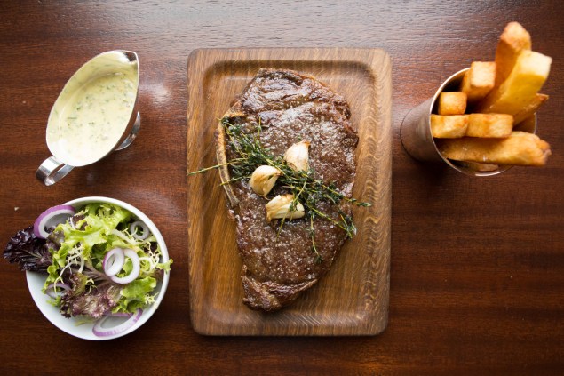 A dry aged New York strip steak served with French fries, bernaise sauce and a mixed leaf salad at The Clock Tower in the New York Edition hotel in the Flatiron District. (Photo: Arman Dzidzovic/New York Observer)
