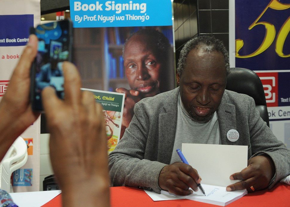 Internationally celebrated author, playwright and critic, Kenyan Ngugi wa Thiong'o is photographed by a fan using a mobile phone on June 13, 2015 during a book signing to celebrate the golden jubilee of his first book 'Weep Not Child'  in the Kenyan capital, Nairobi. A 2014 nominee for the Nobel Prize for literature, Ngugi's 50 year literary career, fraught with dangers, has seen him jailed and therafter forced into exile by successive regimes of the time and his latest visit is seen as a real homecoming after he was received at State House by current President Uhuru Kenyatta who's father, Kenya's powerful first President Jomo Kenyatta jailed Ngugi without trial in 1977 over his critical play Ngaahika Ndeeda, (I will Marry When I Want), before being forced into exile after his release during Kenyatta's successor, President Daniel Arap Moi's rule. "This is not the Kenya of yesterday but a Kenya that needs all your talents. It is time for you to come back and help us build the country," Kenyatta is quoted as saying in the local press.  AFP PHOTO/Tony KARUMBA       