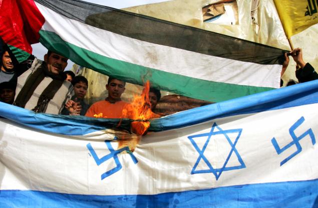 Palestinian protestors burn a makeshift Israeli flag, bearing Nazi swastikas on each side of the Star of David, during a demonstration against Israel's continuing assault on Gaza in the refugee camp of Ain el-Hilweh near the southern Lebanese port city of Sidon on December 30, 2008. Arab capitals have been the scene for daily protests since December 27 against the continuing Israeli onslaught in the Gaza Strip that has killed more than 360 Palesitnians. Israel today readied troops on the Gaza border and warned its assault on Hamas could last for weeks, as jets pummelled Islamist targets for a fourth day amid a diplomatic push for a truce. AFP PHOTO/MAHMOUD ZAYAT (Photo credit should read MAHMOUD ZAYAT/AFP/Getty Images)