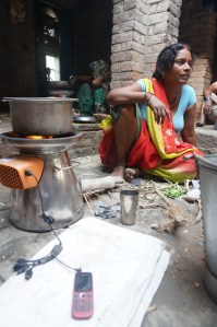 A woman charges her mobile while cooking. (Photo: Biolite)