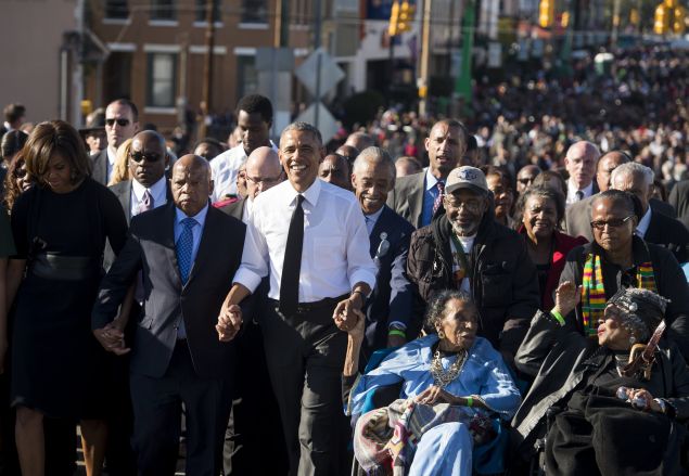 US President Barack Obama walks alongside Amelia Boynton Robinson (2nd-R), one of the original marchers, First Lady Michelle Obama (L), and US Representative John Lewis (2nd-L), Democrat of Georgia, and also one of the original marchers, across the Edmund Pettus Bridge to mark the 50th Anniversary of the Selma to Montgomery civil rights marches in Selma, Alabama, March 7, 2015. The event commemorates Bloody Sunday, when civil rights marchers attempting to walk to the Alabama capital of Montgomery to end voting discrimination against African Americans, clashed with police on the bridge. AFP PHOTO / SAUL LOEB (Photo credit should read SAUL LOEB/AFP/Getty Images)