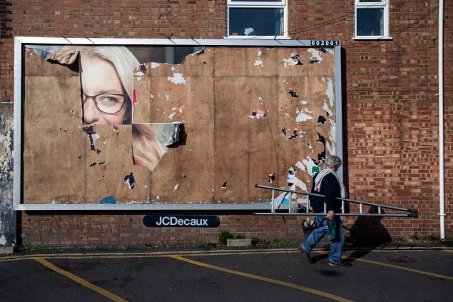 LONDON, ENGLAND - FEBRUARY 10: A window cleaner walks past a billboard with a small portion of an old advert remaining on February 10, 2014 in London, England. (Photo by Oli Scarff/Getty Images)