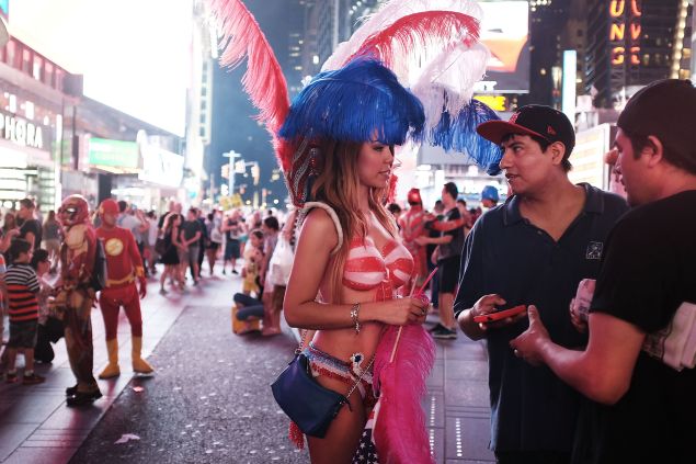 A body-painted model approaches two men in Times Square (Photo: Spencer Platt for Getty Images).