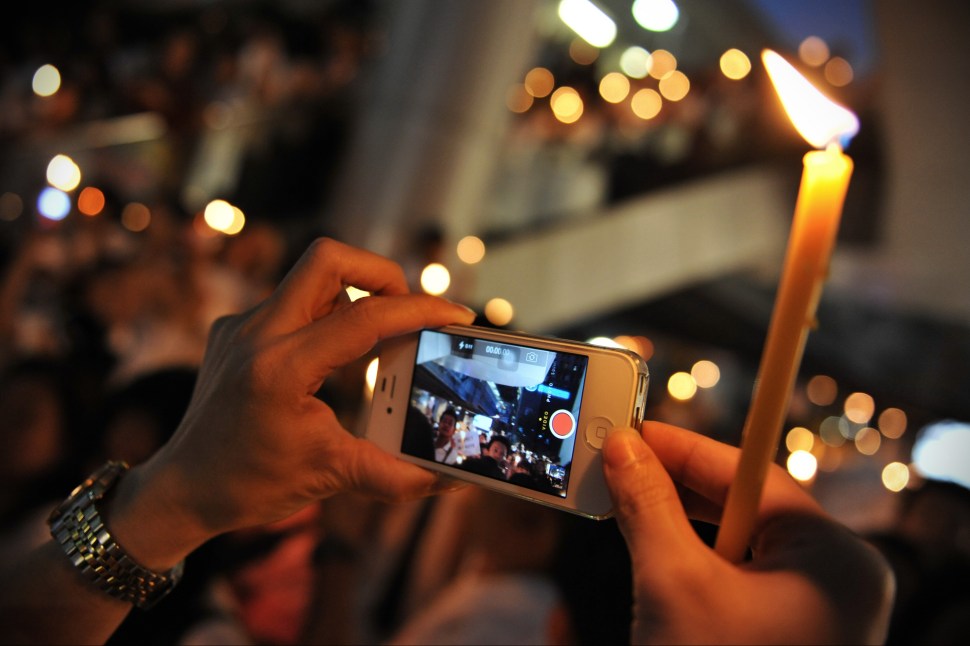 BANGKOK, THAILAND - JANUARY 10: A pro-election activist uses a smartphone to video a city centre rally on January 10, 2014 in Bangkok, Thailand. Over a thousand pro-election activists gathered in Bangkok's shopping district to show support for Thailand's upcoming snap-poll on February 2 and also voice opposition to a planned shutdown of Bangkok by anti-government groups. In Thailand's latest round of political turmoil, which has lasted over two months, anti-government groups have announced they will shutdown Bangkok early next week in an attempt to pressure the government to resign and derail the February election. (Photo by Rufus Cox/Getty Images)