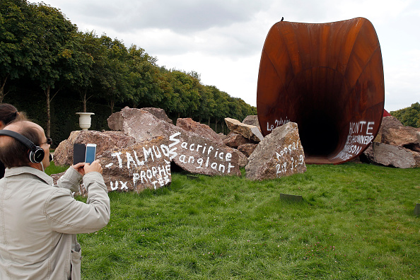 A visitor takes a picture of "Dirty Corner" by artist Anish Kapoor, vandalized for the second time in the gardens of the Chateau de Versailles. (Photo by Chesnot/Getty Images)