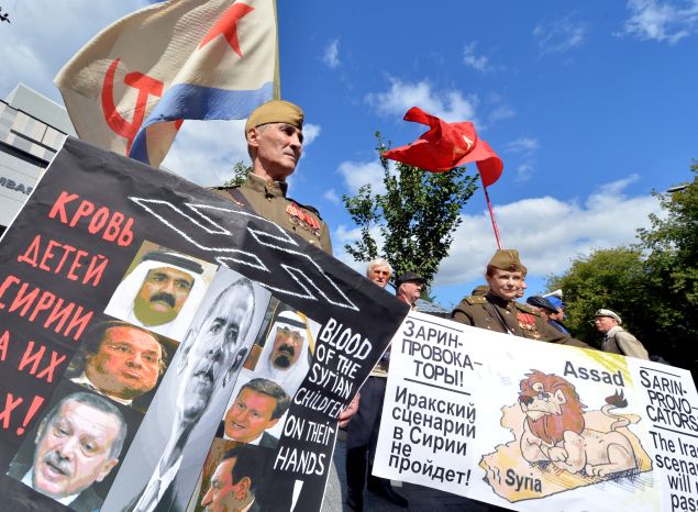A Soviet army veteran holds a placard depicting heads of state and reading "Blood of Syrian children on their hands" during a protest outside the US embassy in Kiev on September 5, 2013. The rally organized by Ukrainian left-wing parties demanded a halt to a potential US attack against Syria. AFP PHOTO/ SERGEI SUPINSKY (Photo credit should read SERGEI SUPINSKY/AFP/Getty Images)