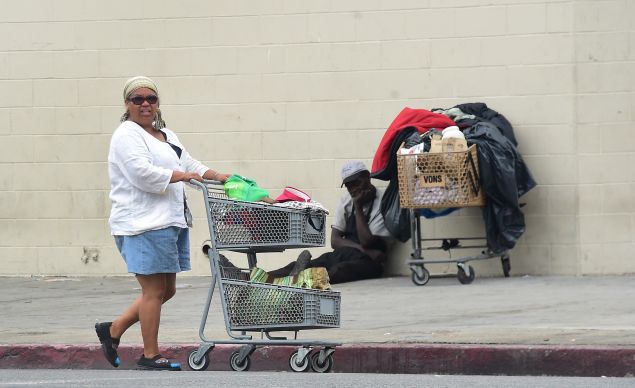 A homeless woman pushes her cart of belongings along a street in Los Angeles, California on August 25, 2015. According to a report released today by the Economic Roundtable, a nonprofit research group in Los Angeles, some 13,000 people tumble into homelessness every month in Los Angeles County, where the latest official count of the homeless found 44,000 people living along county streets during a three-day period in January, a increase of 12% in two years. AFP PHOTO /FREDERIC J.BROWN (Photo credit should read FREDERIC J. BROWN/AFP/Getty Images)