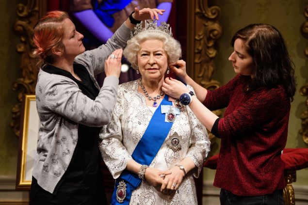 Stylists Jane Anderson and Luisa Compabassi pose with the re-styled wax figure of Britain's Queen Elizabeth II. (Photo: LEON NEAL/AFP/Getty Images)