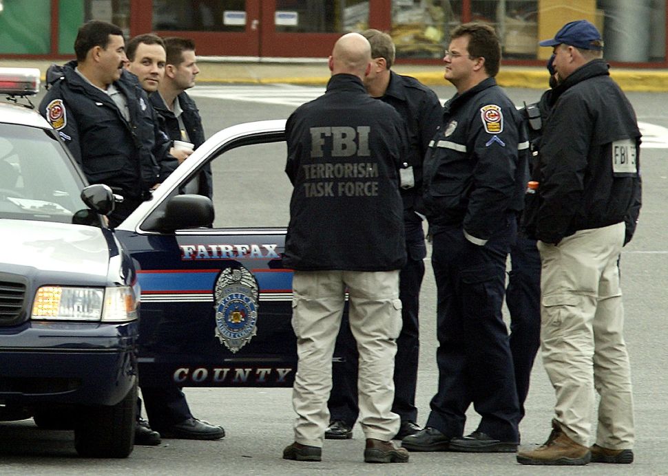 FALLS CHURCH, UNITED STATES: Members of the FBI talk with Fairfax police officers in the parking lot of the Home Depot construction supply store in Falls Church, VA, 15 October 2002. FBI analyst Linda Franklin, 47, of Arlington, Virginia, was killed late 14 October by a gun matched to the serial sniper who has been killing people throughout the Washington, DC, Maryland, and Virginia area with a high powered rifle. AFP PHOTO/Paul J. Richards (Photo credit should read PAUL J. RICHARDS/AFP/Getty Images)