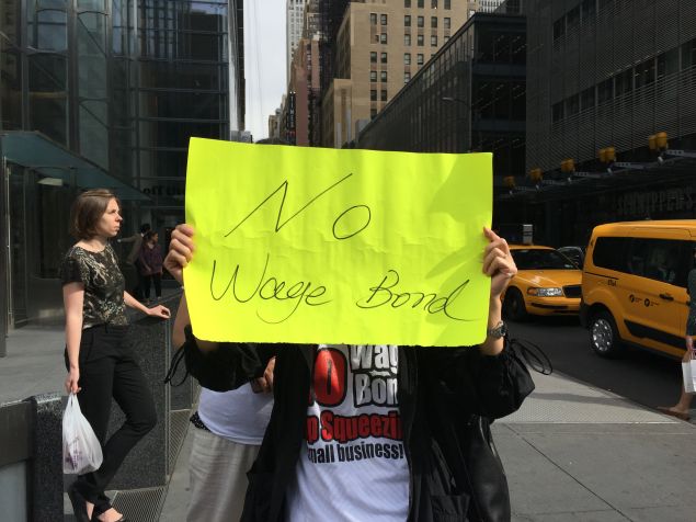 A nail salon worker holds a protest sign outside of The Times building on 8th ave. (Photo: Sage Lazzaro for Observer)