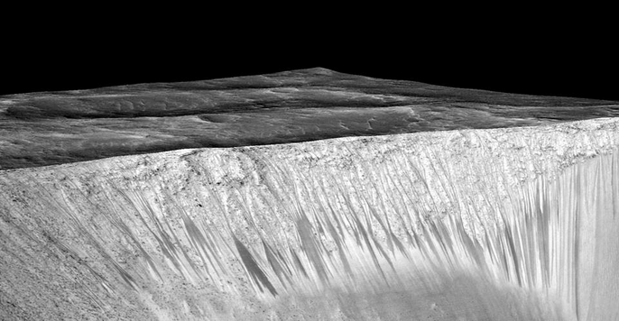 Dark narrow streaks called recurring slope lineae emanating out of the walls of Garni crater on Mars. The dark streaks here are up to a few hundred meters in length and are hypothesized to be formed by the flow of salt water. Credit: NASA/JPL/University of Arizona
