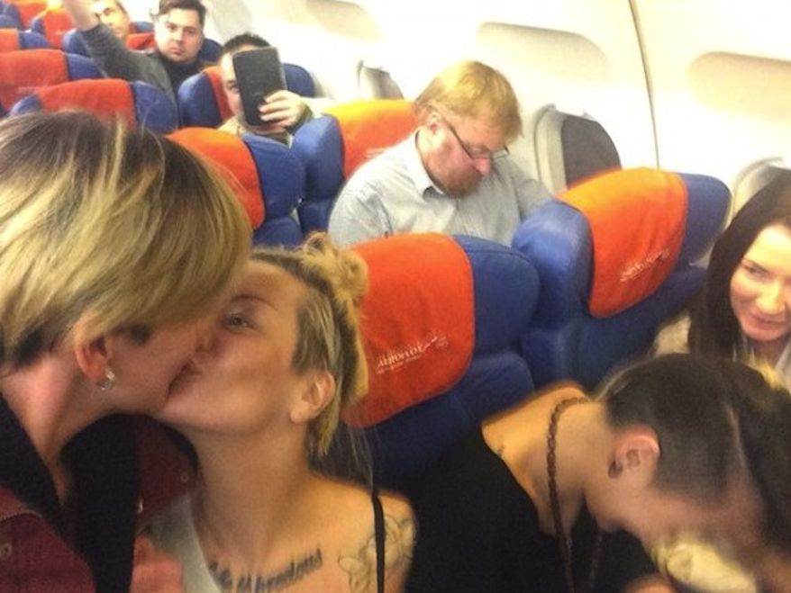 Lesbian activists who happened to be on a plane with anti-gay Russian lawmaker Vitaly Milonov arranged for him to photobomb them while kissing. (screencap CNN)