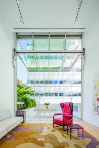 The all-glass wall opens up to reveal one of two private outdoor spaces in the unit. (The Corcoran Group)