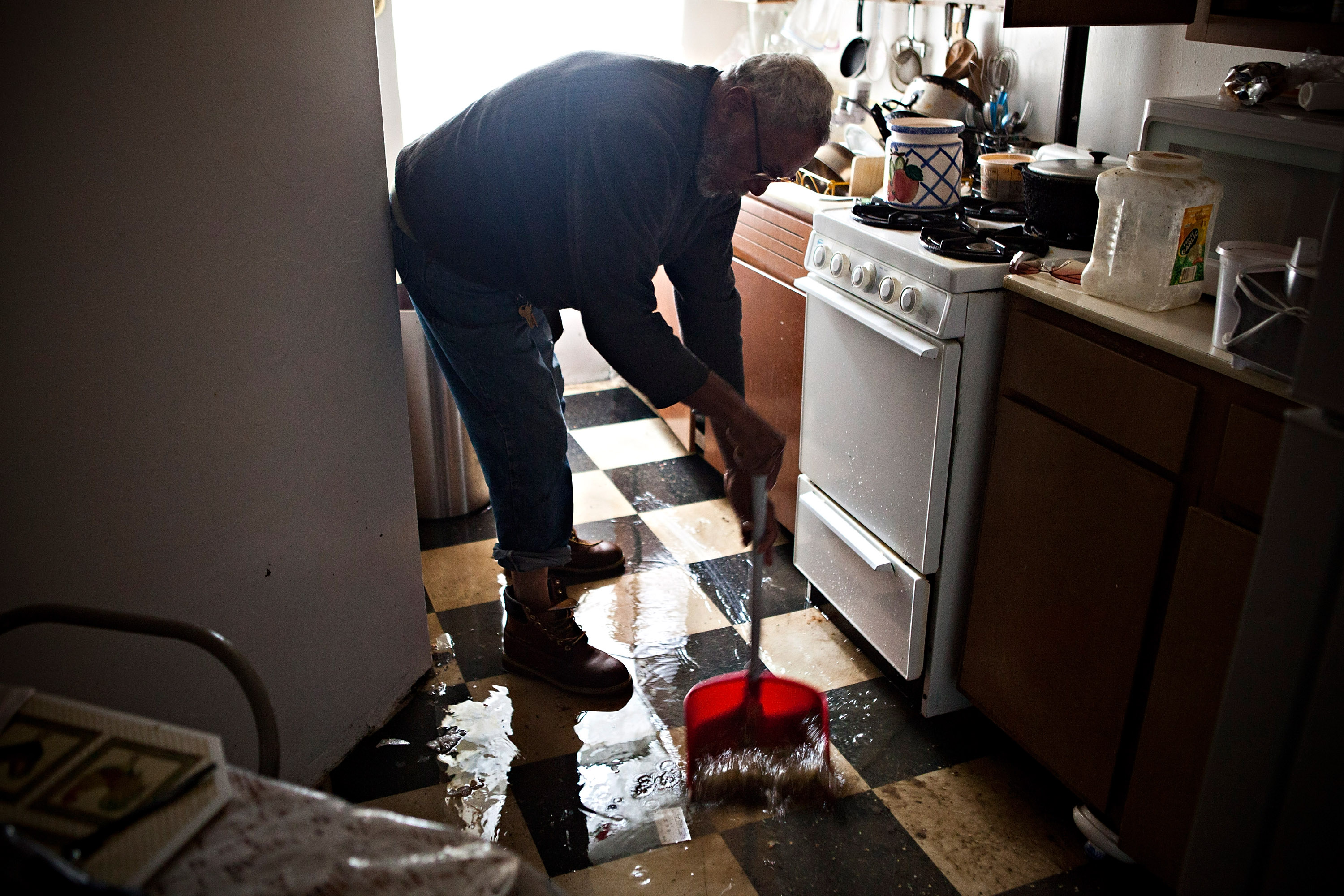 Jolito Ortiz helps sweep water out of his friend's apartment on the Lower East Side after Hurricane Sandy. (Photo by Andrew Burton/Getty Images)