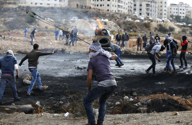 Palestinian protesters throw stones towards Israeli security orces during clashes at the northern entrance of the West Bank town of Al-Bireh, on the northern outskirts of Ramallah, in the West Bank, on October 27, 2015. Stabbings and violent protests have become daily occurrences since simmering tensions over the status of the Al-Aqsa mosque compound in Jerusalem's Old City boiled over in early October, leaving scores dead. AFP PHOTO / ABBAS MOMANI (Photo credit should read ABBAS MOMANI/AFP/Getty Images)