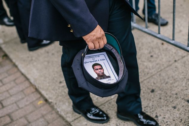 A police officer keeps Randolph Holder's funeral announcement in his hat (Photo by Christopher Gregory/Getty Images).