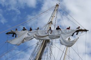 A crew unfurls the mast aboard Peacemaker.