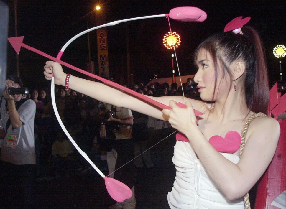 MANILA, PHILIPPINES: A Filipina model wearing a cupid outfit prepares to shoot a red arrow to signal the start of "Lovapalooza," Manila's Valentine's Day kissing event on a street by the famous Manila Bay, 14 February 2004. More than 5,000 Filipino couples kissed simultaneously for 10 seconds to welcome in Valentine's Day and set a new world record, organizers said. AFP PHOTO/JAY DIRECTO (Photo credit should read JAY DIRECTO/AFP/Getty Images)