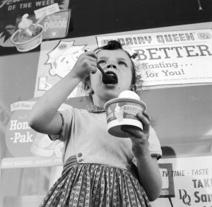 circa 1955: A young girl eating ice cream outside a Dairy Queen store. (Photo by Jacobsen /Three Lions/Getty Images)