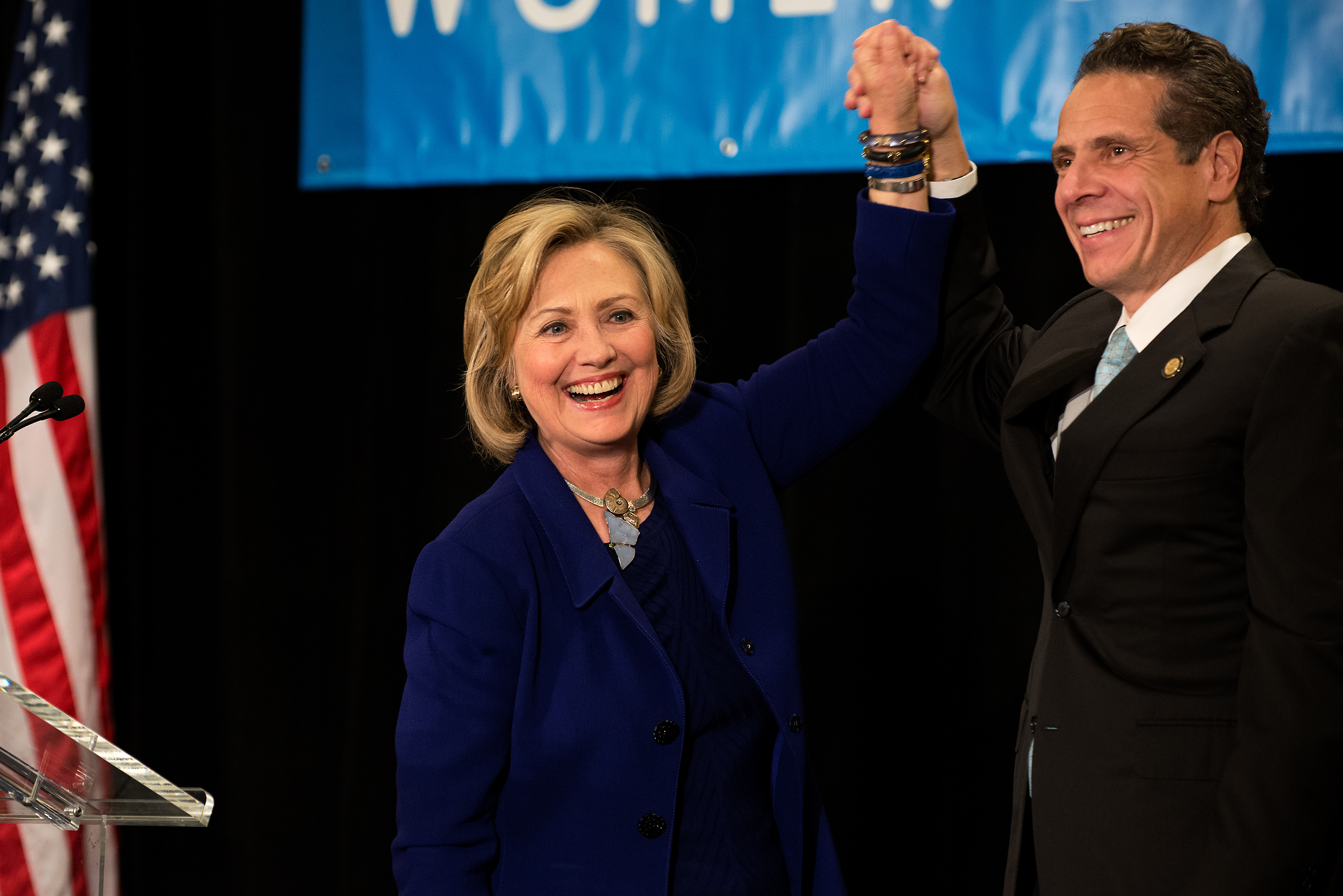 Former U.S. Secretary of State and U.S. Sen. Hillary Rodham Clinton raises the hand of New York Gov. Andrew Cuomo at a Cuomo campaign event in 2014. (Photo by Bryan Thomas/Getty Images)